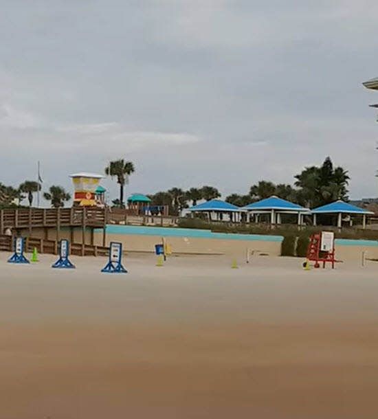 A beach area with sand and a building in the background.