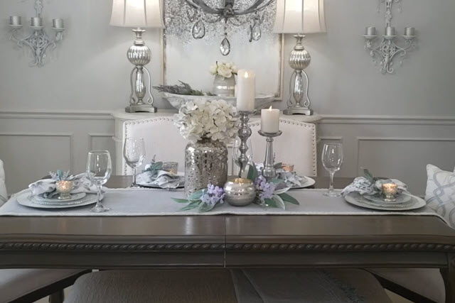A dining room with a white table and silver chairs.
