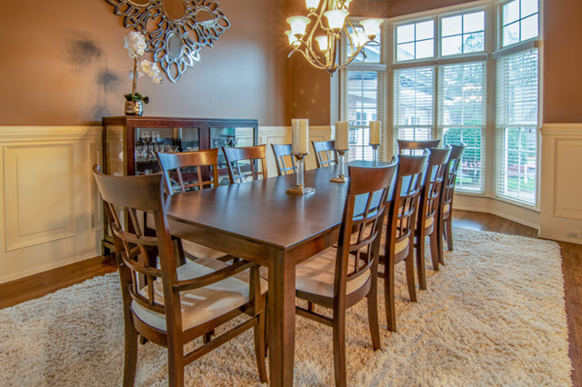 A dining room with a large table and chairs.