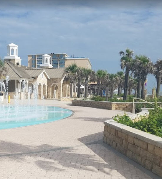 A fountain in front of a building with palm trees.