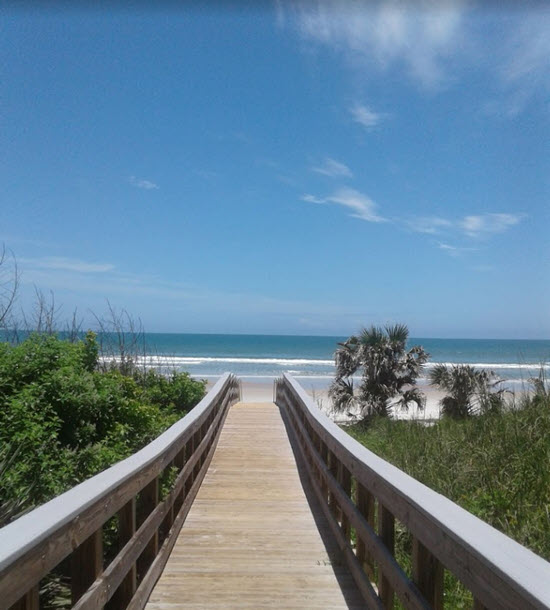 A wooden walkway leading to the beach on a sunny day.