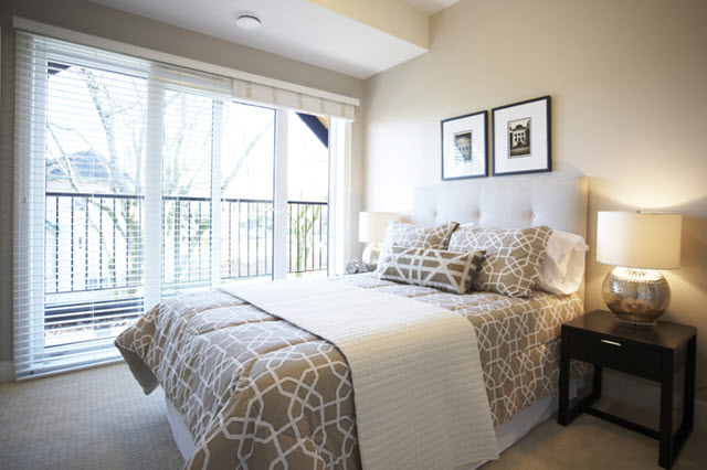 A bedroom with a beige bed and a sliding glass door.