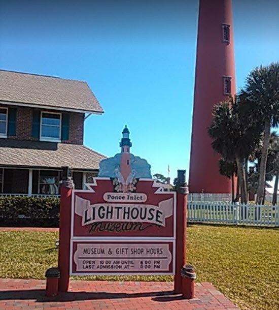 A sign for the lighthouse in front of a house.